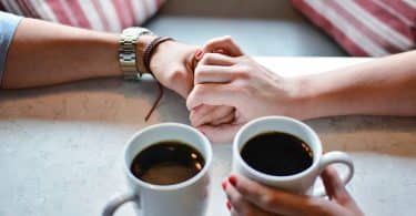 tasses de café et couple qui se donne la main
