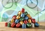 Tas de capsules de café en aluminium colorées empilées sur une table en bois avec un arrière-plan écologique.