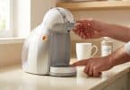 Une personne effectue le détartrage d'une machine à café Dolce Gusto blanche affichant un voyant orange.