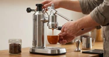 Mains utilisant une machine à expresso manuelle en acier inoxydable pour verser un café dans une tasse orange.