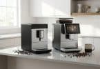 Deux machines à café Melitta modernes posées sur un comptoir de cuisine lumineux avec des grains de café éparpillés.