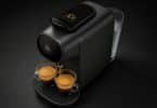 Machine à café noire L'OR Barista préparant deux expressos dans des tasses en verre sur fond sombre.