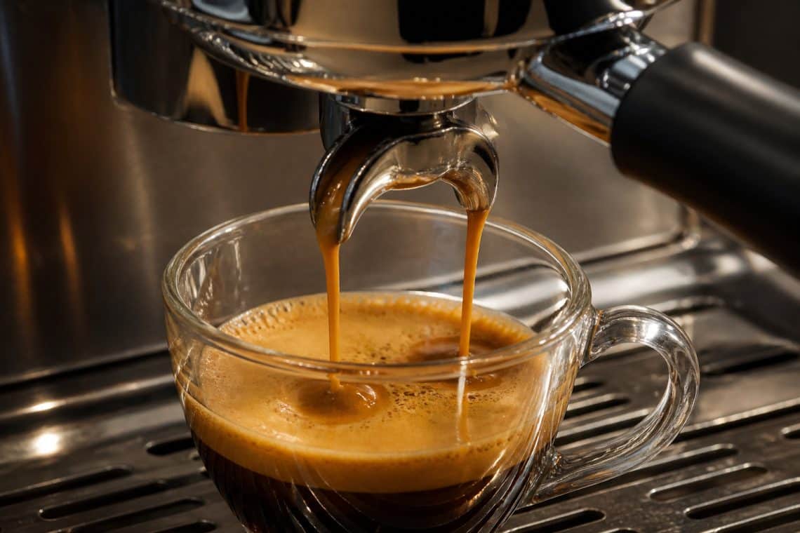 Gros plan sur deux filets de caf&eacute; espresso coulant d'une machine dans une tasse en verre transparente.