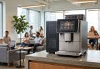 Machine à café professionnelle sur un comptoir dans un espace de coworking lumineux avec des employés en arrière-plan.