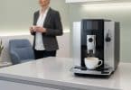 Machine à café automatique Jura sur un comptoir dans une salle d'attente avec une femme en arrière-plan.