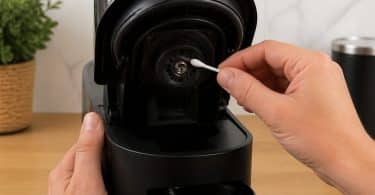 Une personne nettoie le lecteur de code-barres d'une machine Nespresso Vertuo avec un coton-tige.