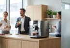 Des collègues discutent autour d'une machine à café automatique Jura dans une cuisine de bureau moderne.