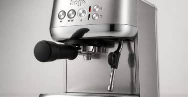 Machine à expresso Sage compacte en acier brossé avec porte-filtre noir et buse vapeur sur fond gris clair.