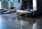 Une machine à café DeLonghi fuit sur le plan de travail, formant une flaque d'eau avec un torchon à proximité.