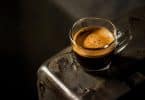 Une tasse d'expresso fraîchement préparé avec une crème épaisse, posée sur une surface métallique sombre et texturée.