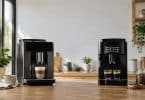 Deux machines à café automatiques posées sur une table en bois dans une cuisine lumineuse.