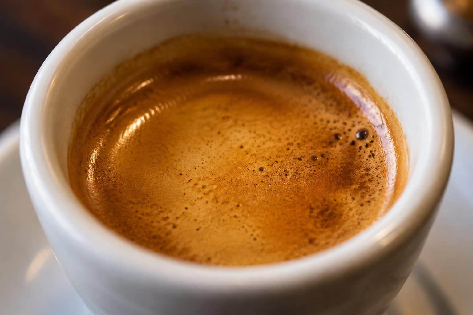 Gros plan sur une tasse blanche remplie de caf&eacute; recouvert d&rsquo;une mousse dor&eacute;e.